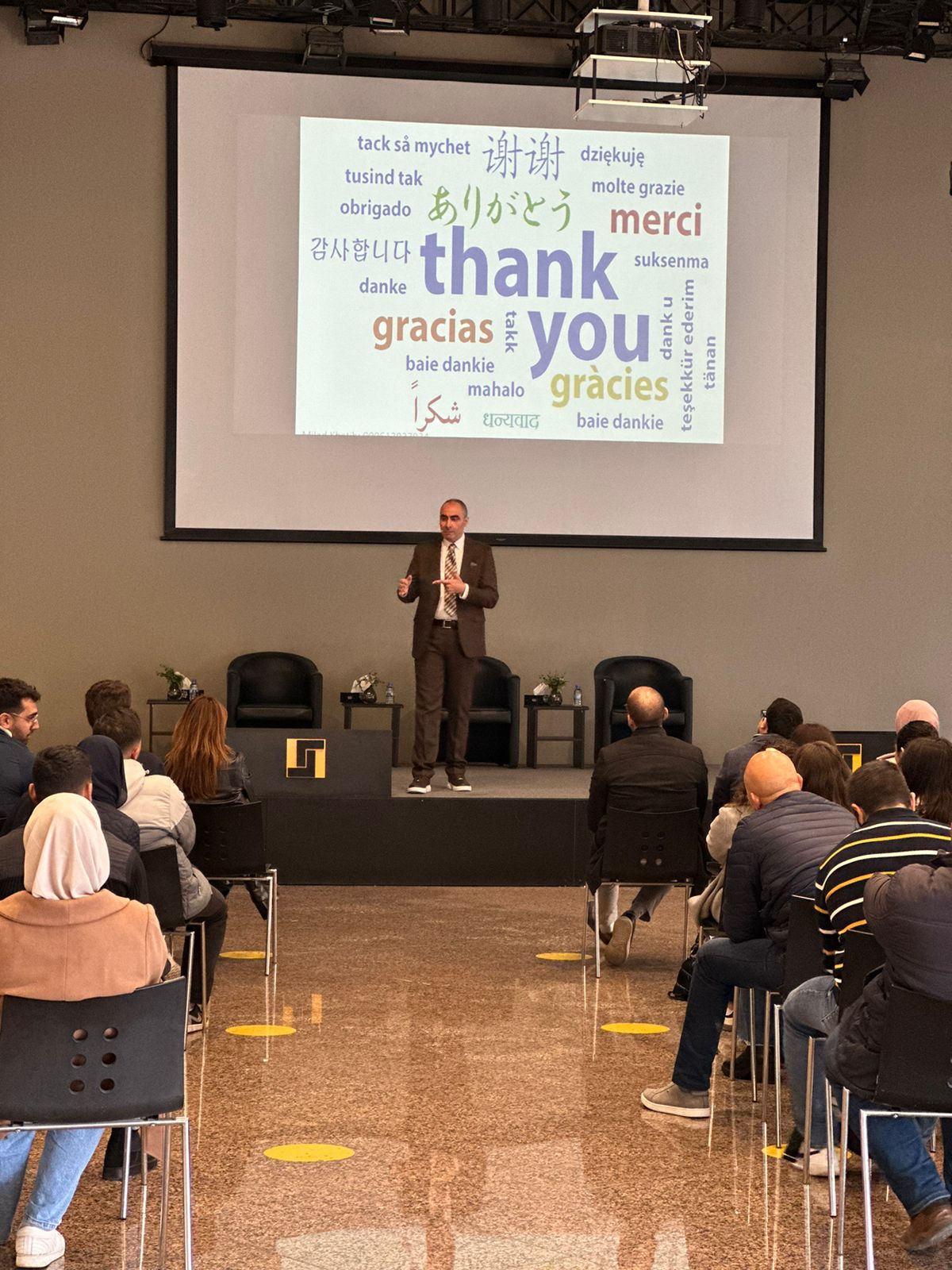 Dr. Khatib presenting to international audience with multilingual thank you slide